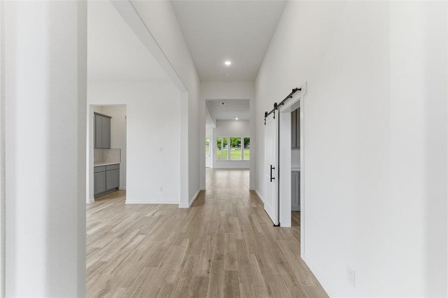 A long hallway featuring light-toned wood-look flooring and white walls