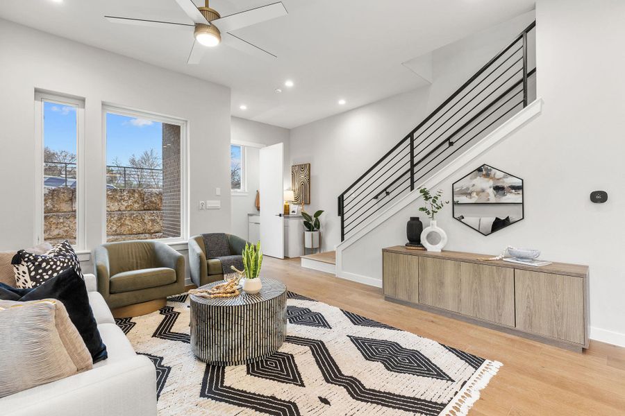 Living area with baseboards, light wood-style flooring, ceiling fan, stairway, and recessed lighting