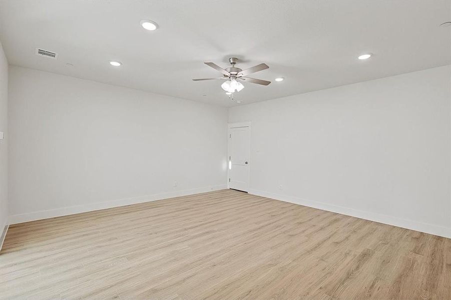 Empty room with light wood-style floors, a ceiling fan, visible vents, and baseboards