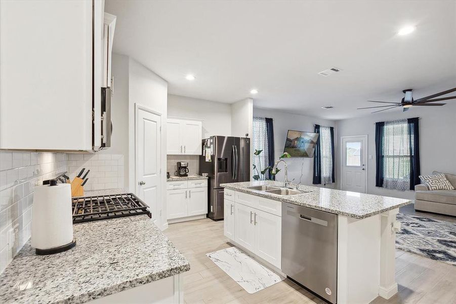 Kitchen with backsplash, ceiling fan, an island with sink, appliances with stainless steel finishes, and sink Kitchen with backsplash, ceiling fan, an island with sink, appliances with stainless steel finishes, and sink