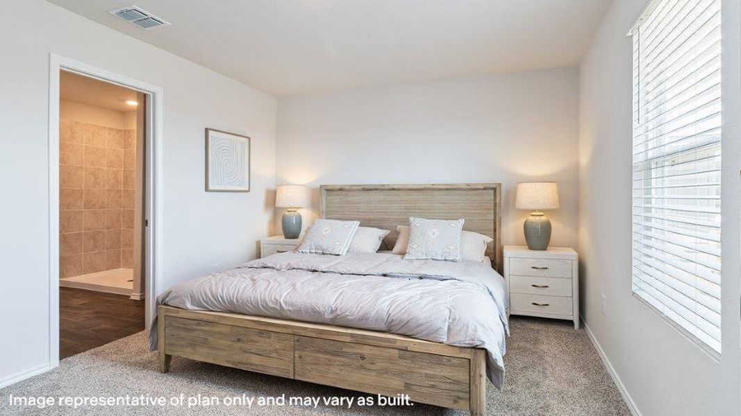 A well-lit bedroom features plush carpeting, offering a cozy retreat adjacent to a tiled bathroom entry. A well-lit bedroom features plush carpeting, offering a cozy retreat adjacent to a tiled bathroom entry.