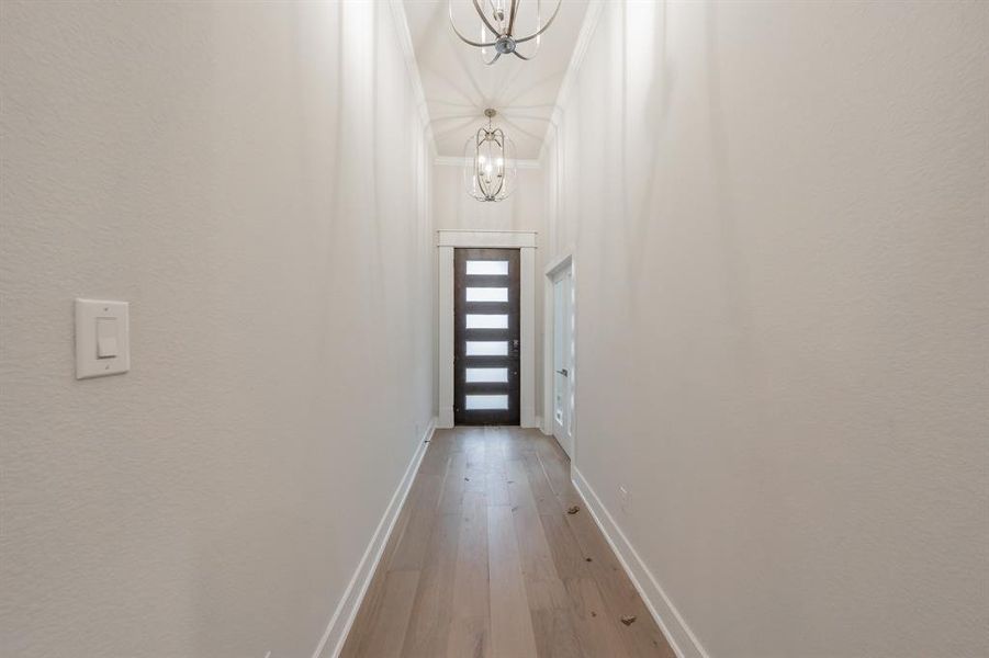 Doorway to outside featuring hardwood / wood-style floors, crown molding, and a chandelier