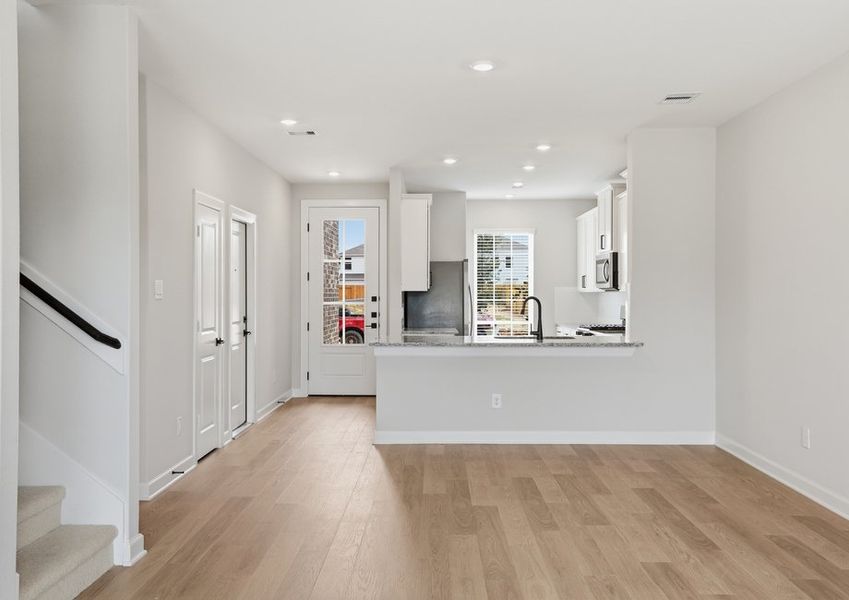 Living room featuring wood-look flooring and a staircase view nearby.