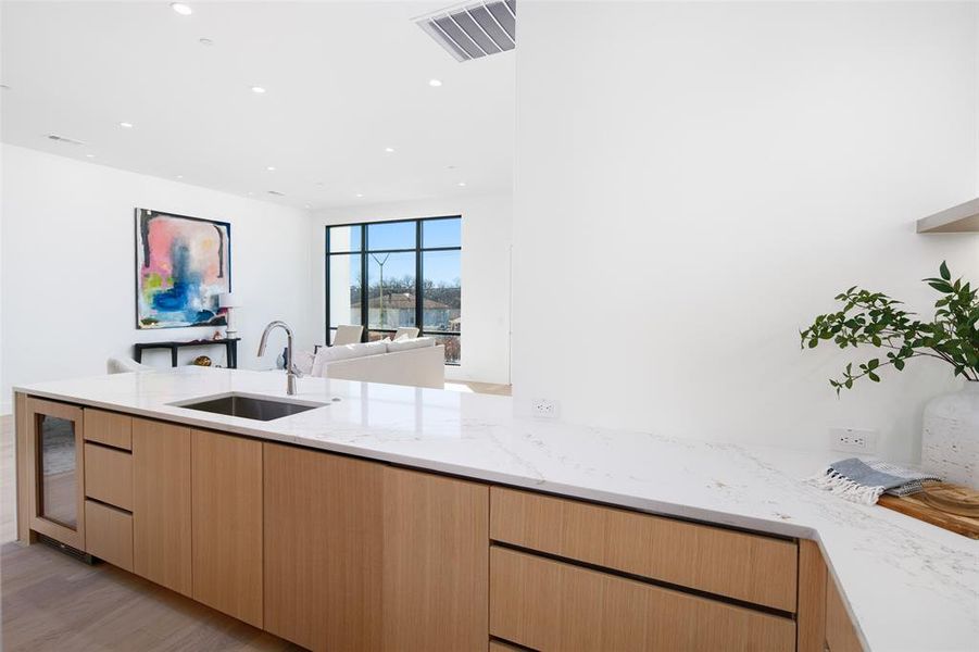 Kitchen featuring light brown cabinetry, light stone counters, sink, and light wood-type flooring