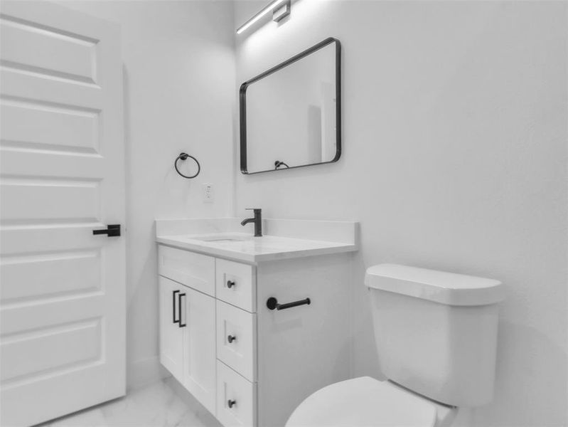 Half bathroom with marble finish floor, toilet, and vanity Half bathroom with marble finish floor, toilet, and vanity