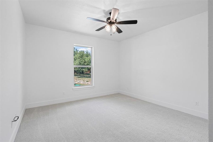 Empty room featuring light colored carpet and a ceiling fan Empty room featuring light colored carpet and a ceiling fan