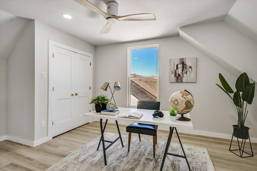 A quiet work-from-home haven features light wood flooring and a refreshing ceiling fan.