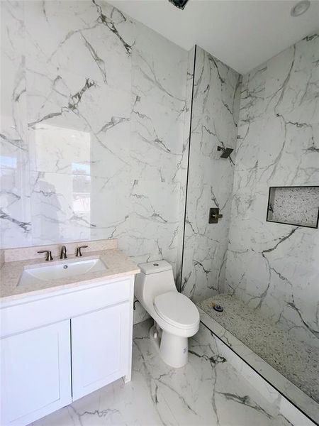 Bathroom with toilet, tile walls, tiled shower, and vanity