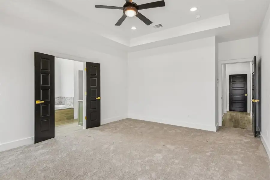 Unfurnished bedroom with a tray ceiling, light colored carpet, ceiling fan, and recessed lighting Unfurnished bedroom with a tray ceiling, light colored carpet, ceiling fan, and recessed lighting