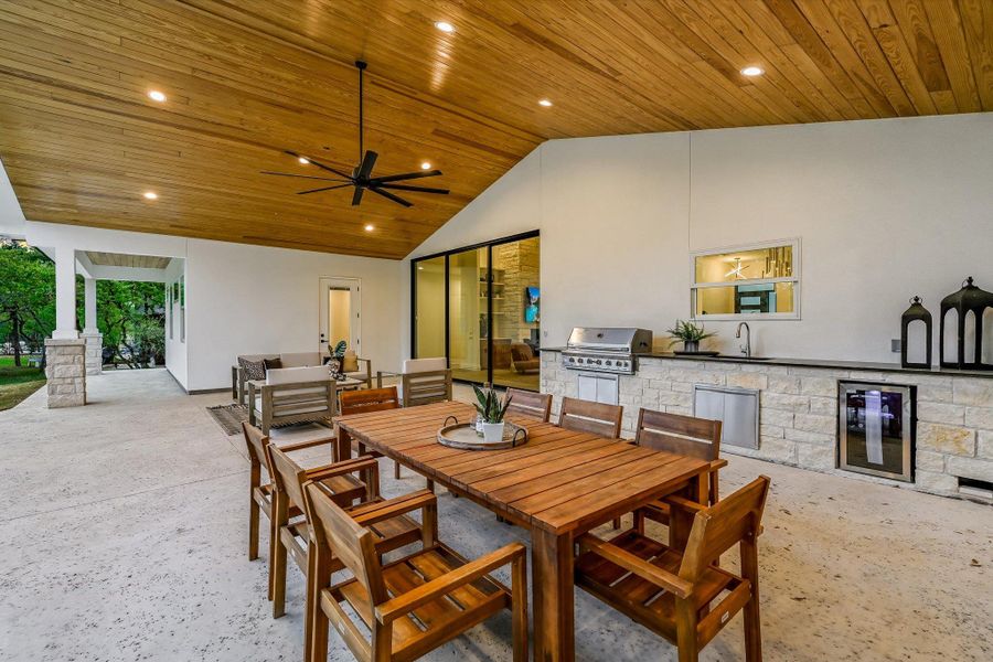 View of patio / terrace with an outdoor kitchen / dining area, a ceiling fan, and beverage cooler
