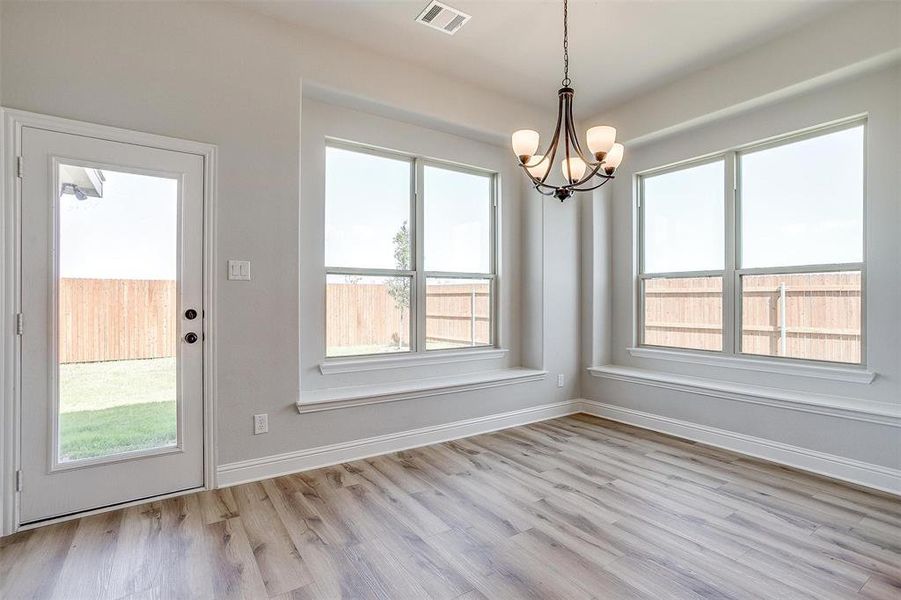 Unfurnished dining area featuring a chandelier and light wood-type flooring