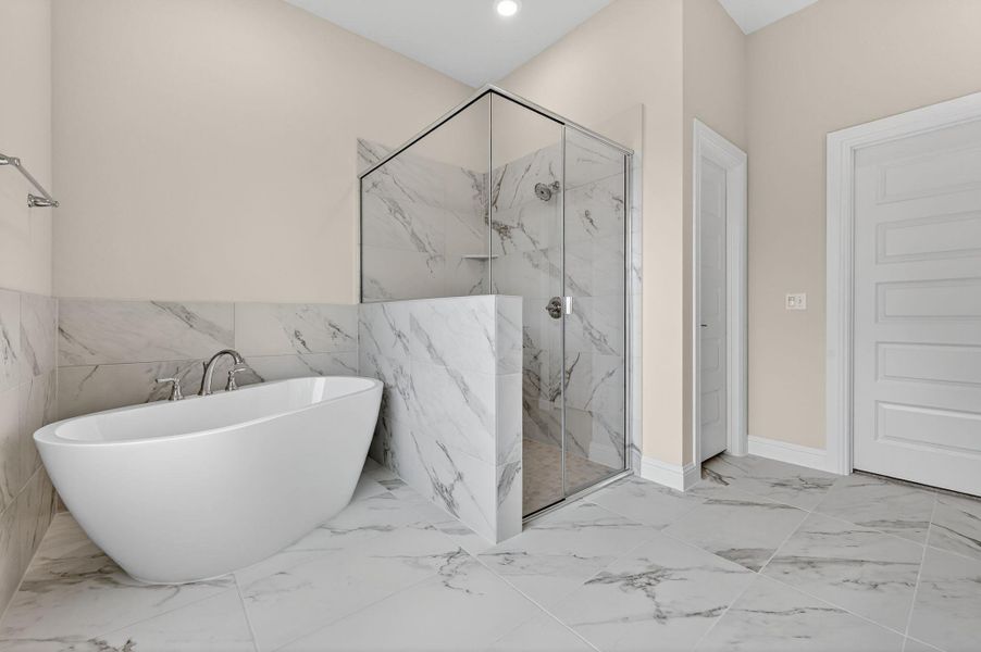 Full bath with light marble finish flooring, a freestanding bath, a marble finish shower, and recessed lighting