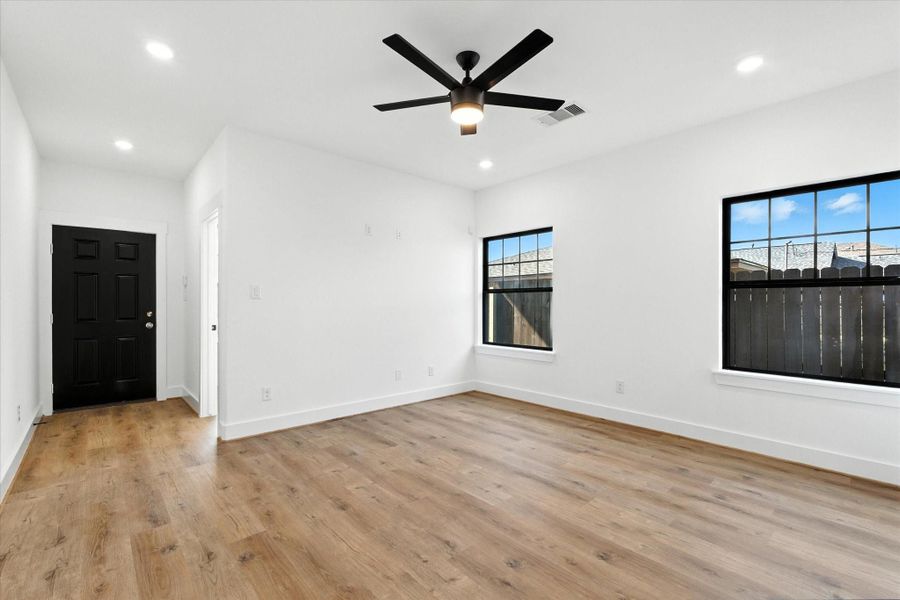 Bright and spacious living area featuring abundant natural light, a ceiling fan, and beautiful luxury vinyl floors that flow seamlessly throughout the first floor.