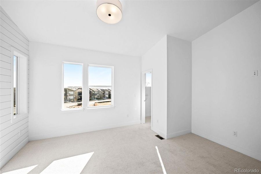 Primary bedroom with vaulted ceilings & upgraded lighting, & large walk-in closet