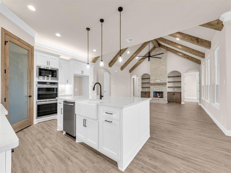 Kitchen with appliances with stainless steel finishes, sink, decorative light fixtures, white cabinets, and an island with sink