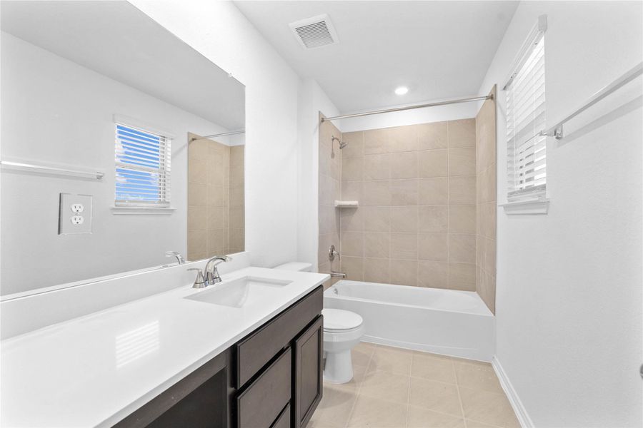 The secondary bathroom showcases tile flooring, a bath/shower combo with a Daltile tile surround, a vanity with knee space and stunning light countertop, a mirror, sleek fixtures, and contemporary finishes throughout. The secondary bathroom showcases tile flooring, a bath/shower combo with a Daltile tile surround, a vanity with knee space and stunning light countertop, a mirror, sleek fixtures, and contemporary finishes throughout.