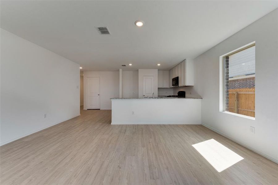 Unfurnished living room featuring sink and light hardwood / wood-style floors