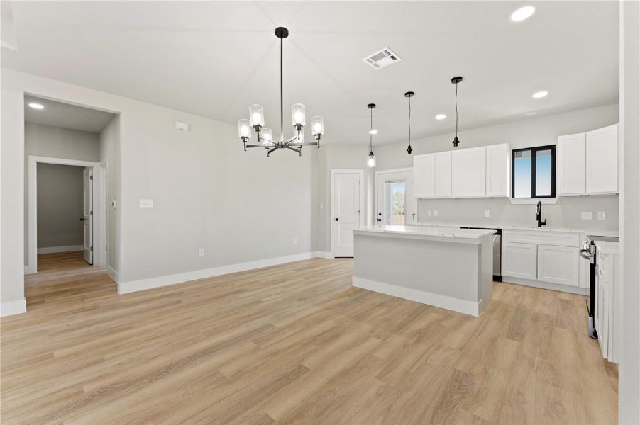 Kitchen with a center island, a chandelier, white cabinets, open floor plan, and stainless steel electric range oven