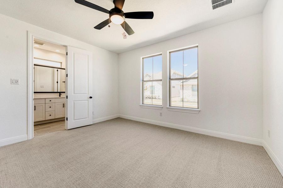 Unfurnished bedroom with light colored carpet, a ceiling fan, and connected bathroom Unfurnished bedroom with light colored carpet, a ceiling fan, and connected bathroom