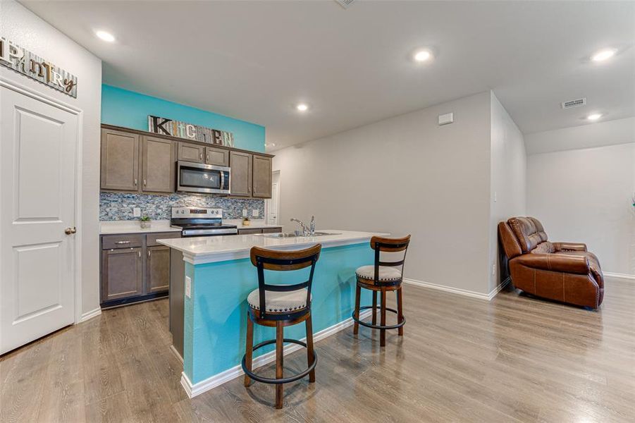 Kitchen featuring a kitchen bar, appliances with stainless steel finishes, sink, a center island with sink, and light hardwood / wood-style floors