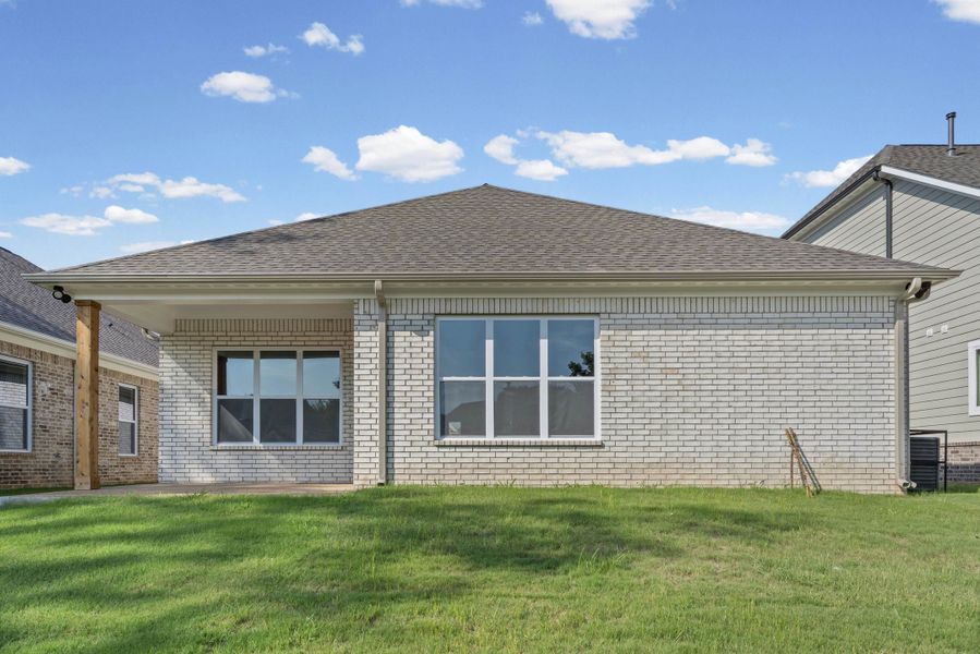 White brick exterior with a covered patio, multiple windows, and a dark shingle roof