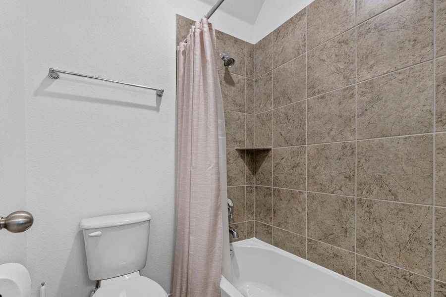 Bathroom featuring toilet and shower / tub combo Bathroom featuring toilet and shower / tub combo