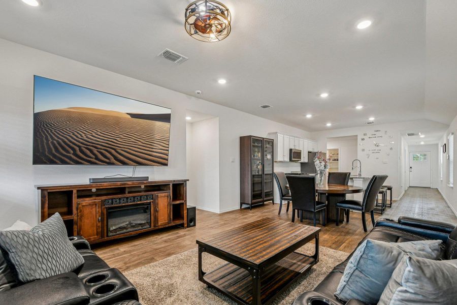 Living room featuring recessed lighting, light wood-type flooring, and a glass covered fireplace