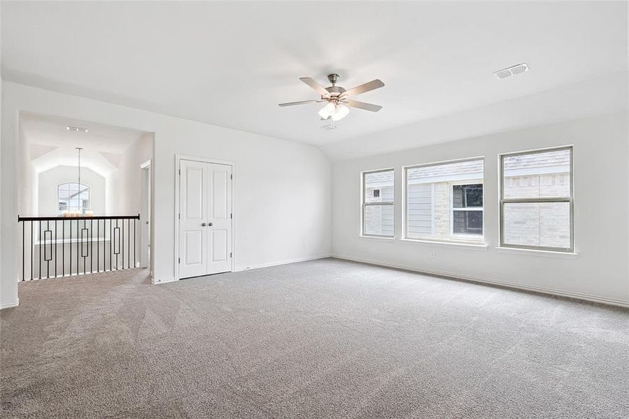 Unfurnished room with carpet, ceiling fan with notable chandelier, and vaulted ceiling