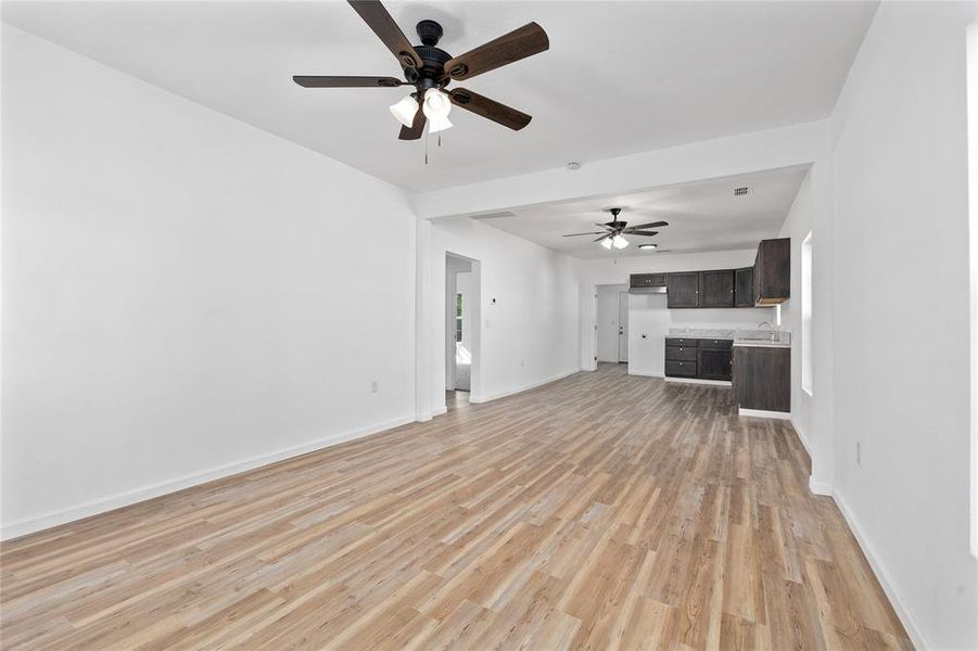 Unfurnished living room with light wood-type flooring and a ceiling fan Unfurnished living room with light wood-type flooring and a ceiling fan