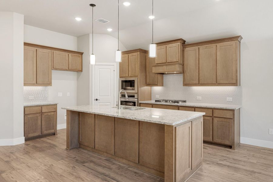 Kitchen with large center island, granite countertops, wood cabinets, and pendant lights over hardwood floors