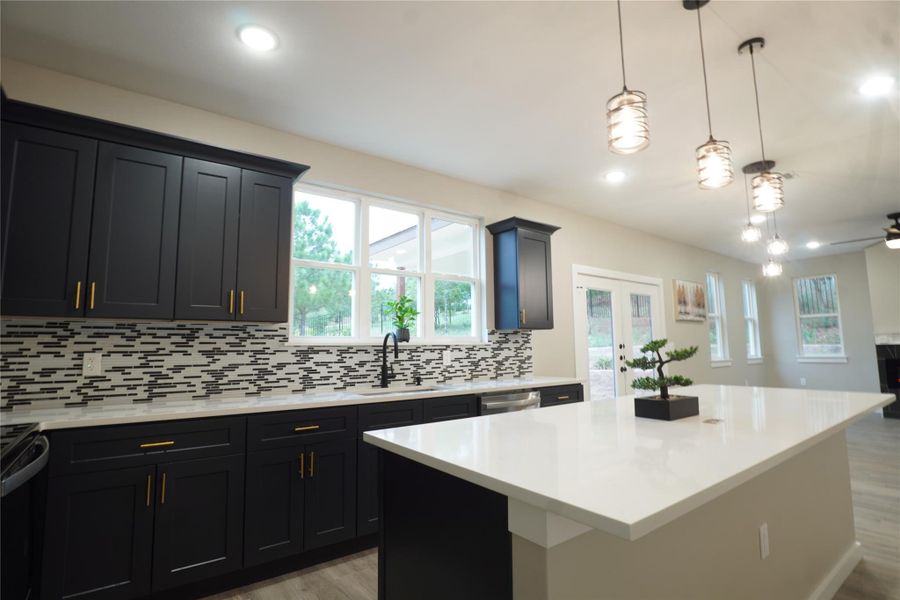 Kitchen featuring decorative light fixtures, french doors, backsplash, dark cabinets, and a kitchen island