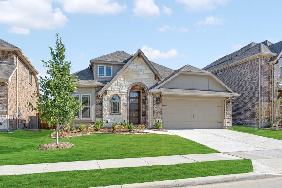 Single-story home with stone and brick exterior, two-car garage, and manicured front lawn