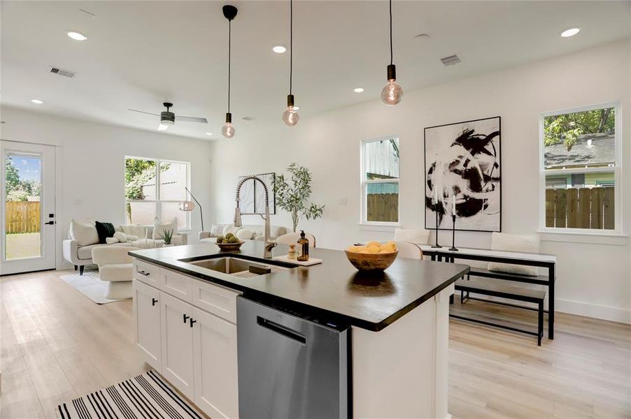 The kitchen island has a stainless steel undermount Kohler sink with retractable faucet and drip accessories, and custom pendant Edison lights.