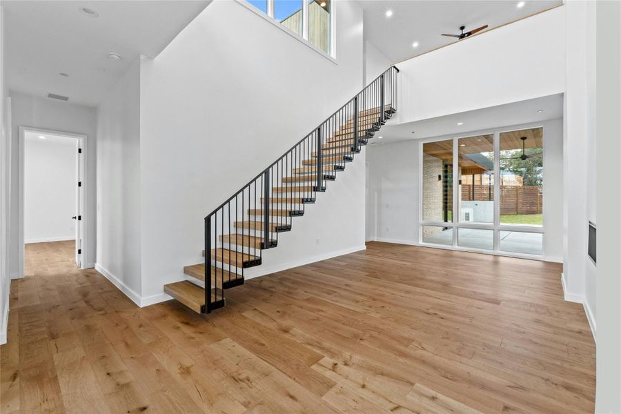 Front foyer (20'Ceiling.) with Floating Stairs and wrought iron railing to the den.  View from the front entry toward the outdoor kitchen and pool area.