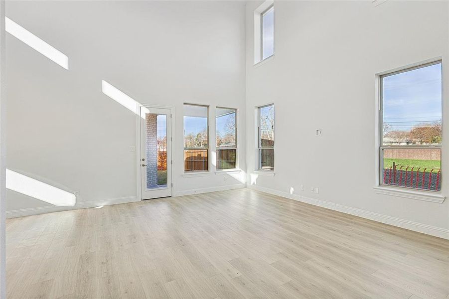 Unfurnished living room with a high ceiling and light wood-type flooring