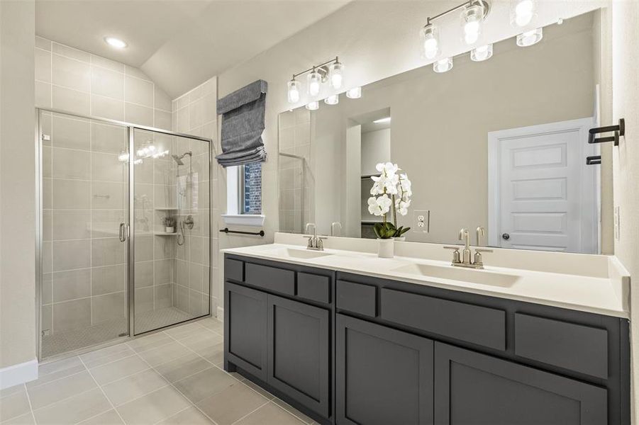 Bathroom featuring double vanity, a sink, a shower stall, and tile patterned floors