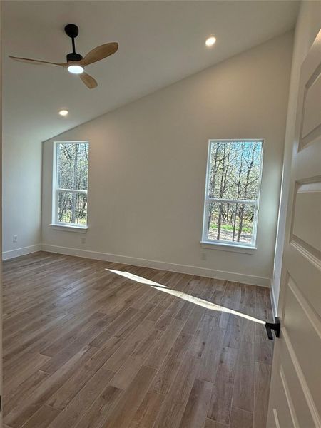 Spare room featuring vaulted ceiling, wood finished floors, a ceiling fan, and recessed lighting