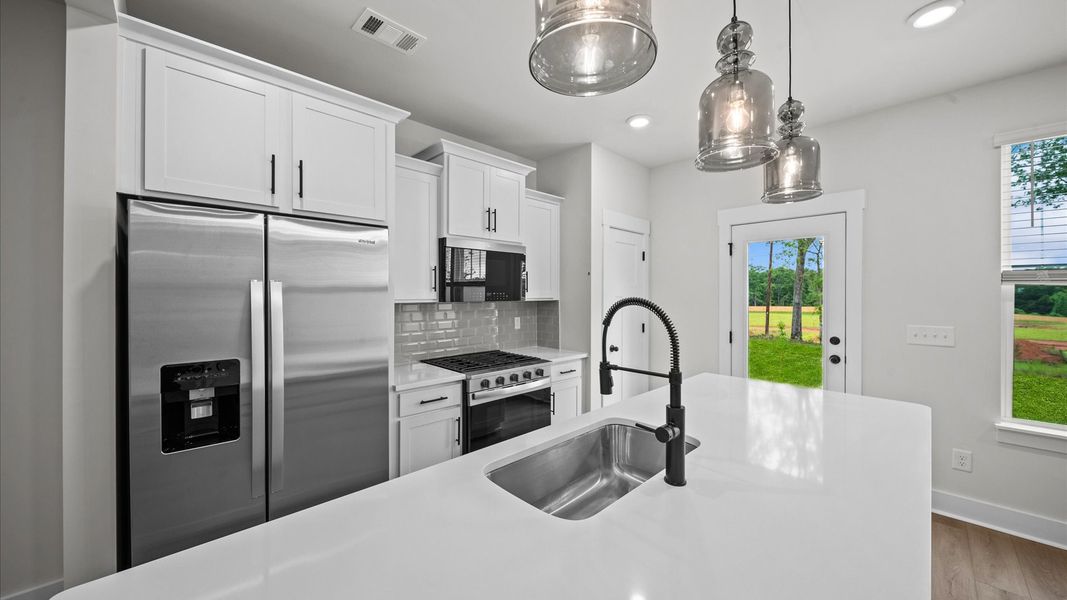 Modern kitchen with 9-foot island with white quartz countertops at Ransdell Pointe by DRB Homes in Spartanburg, SC Modern kitchen with 9-foot island with white quartz countertops at Ransdell Pointe by DRB Homes in Spartanburg, SC