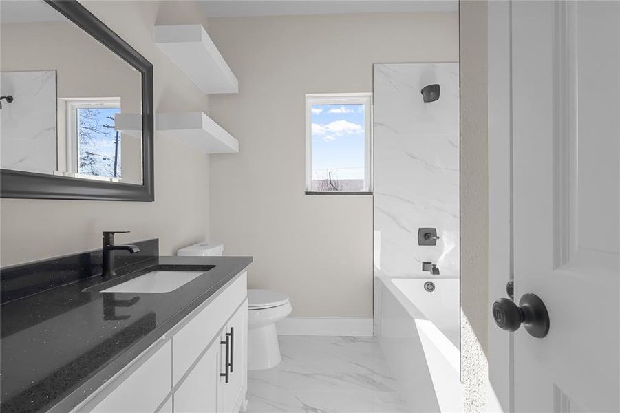 Full bathroom with a healthy amount of sunlight, toilet, tiled shower / bath combo, and vanity