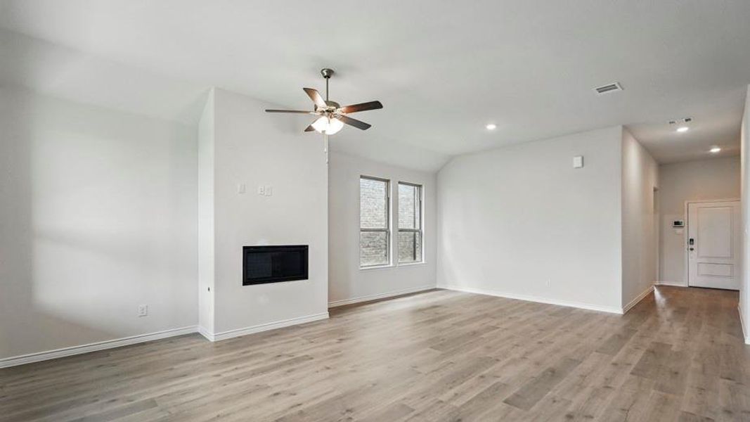 Unfurnished living room featuring a glass covered fireplace, a ceiling fan, vaulted ceiling, light wood-type flooring, and recessed lighting