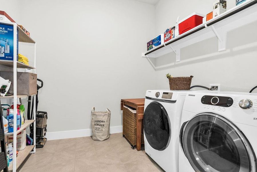 Oversized mudroom/laundry area featuring light-toned tile flooring, electric connections and extra drying space.