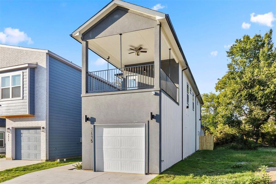 View of side of home with a balcony, a yard, and a garage