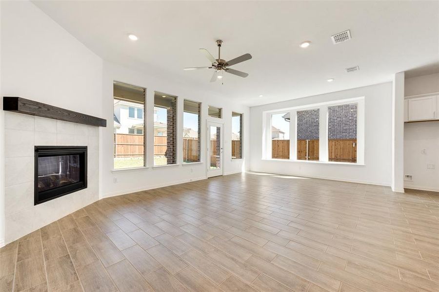 Unfurnished living room with ceiling fan, light hardwood / wood-style floors, and a tile fireplace