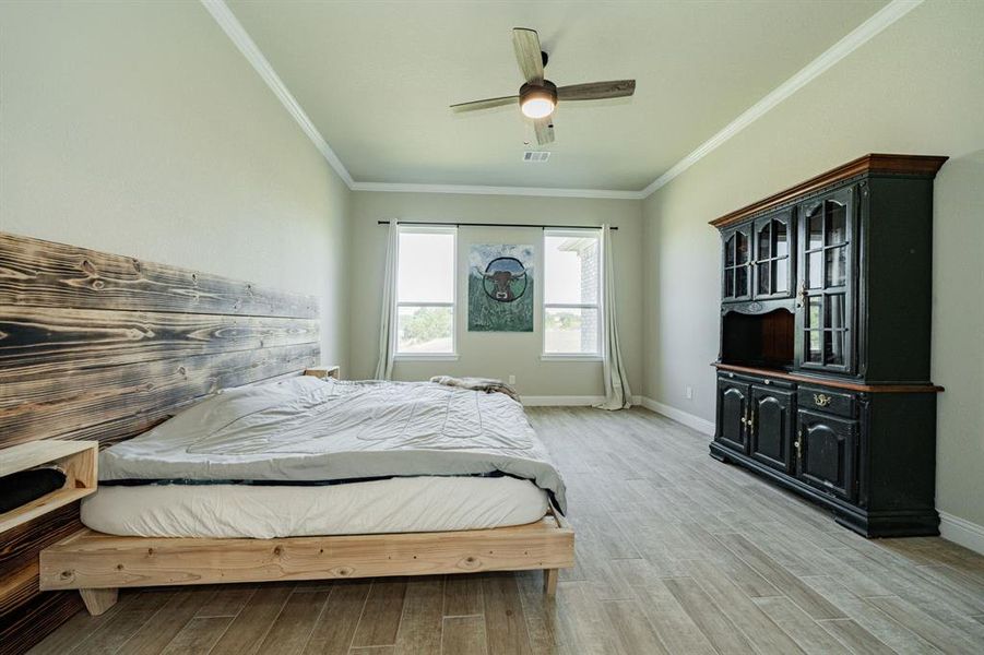Bedroom with crown molding, a ceiling fan, and light wood-type flooring Bedroom with crown molding, a ceiling fan, and light wood-type flooring