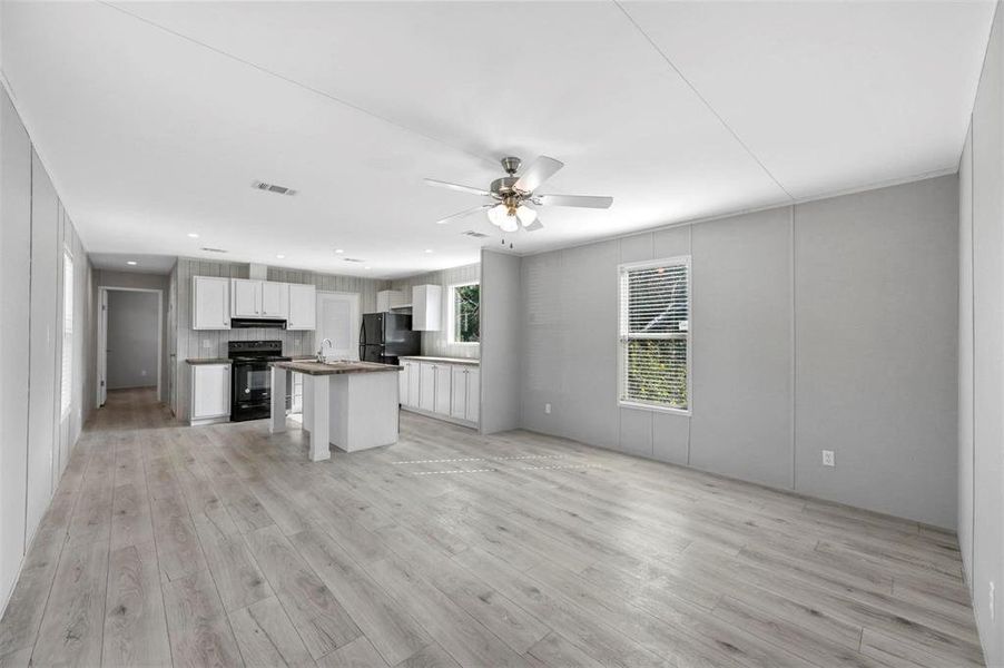 Kitchen with visible vents, under cabinet range hood, white cabinets, black appliances, and a ceiling fan