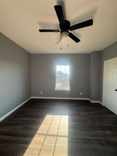 Empty room with dark wood-style flooring and a ceiling fan