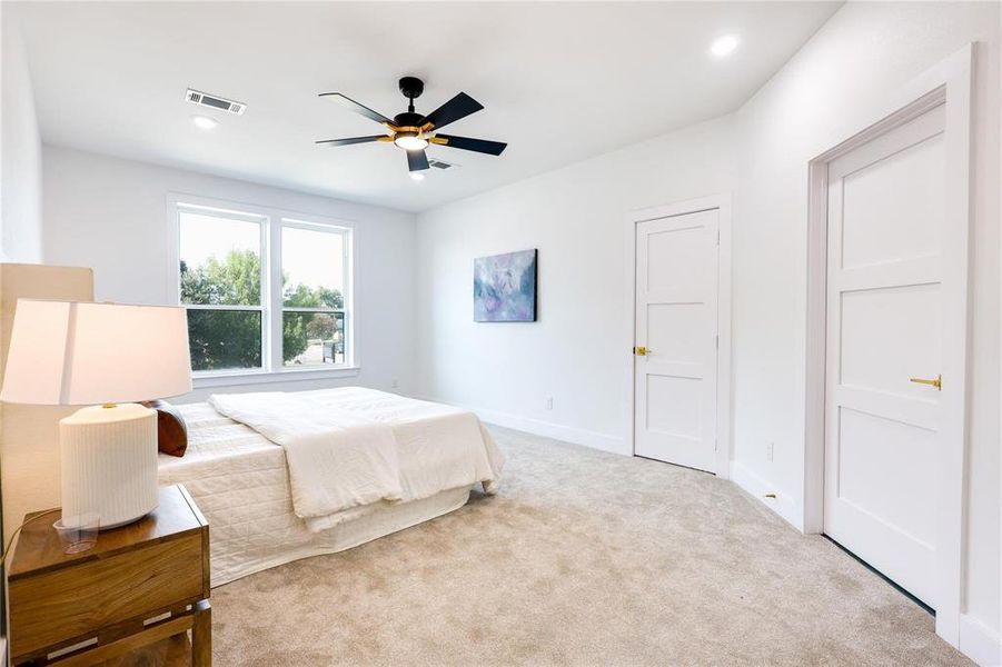 Bedroom with ceiling fan and light carpet