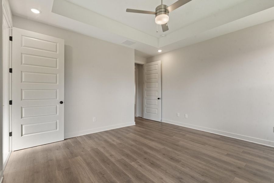 Tray ceiling, recessed lighting, wood-finish flooring, ceiling fan, and paneled doors Tray ceiling, recessed lighting, wood-finish flooring, ceiling fan, and paneled doors