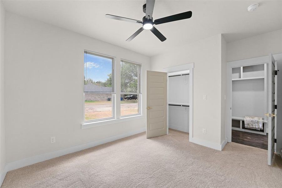 Carpeted bedroom featuring a contemporary ceiling fan with integrated lighting, two windows, and two closet spaces Carpeted bedroom featuring a contemporary ceiling fan with integrated lighting, two windows, and two closet spaces