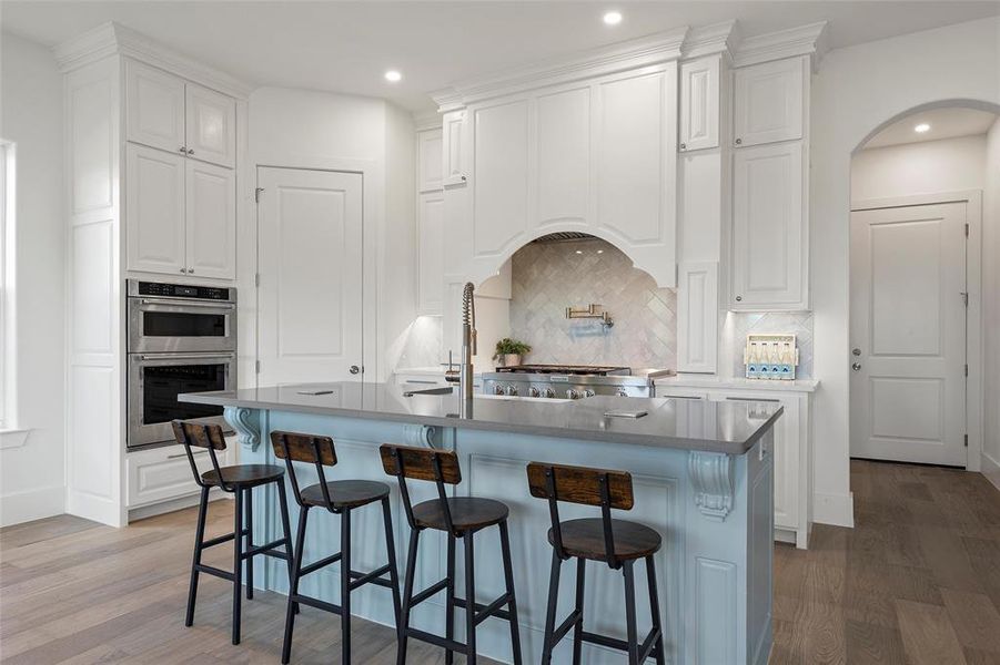 Kitchen with white cabinets, a kitchen bar, dark wood-style floors, backsplash, and recessed lighting Kitchen with white cabinets, a kitchen bar, dark wood-style floors, backsplash, and recessed lighting